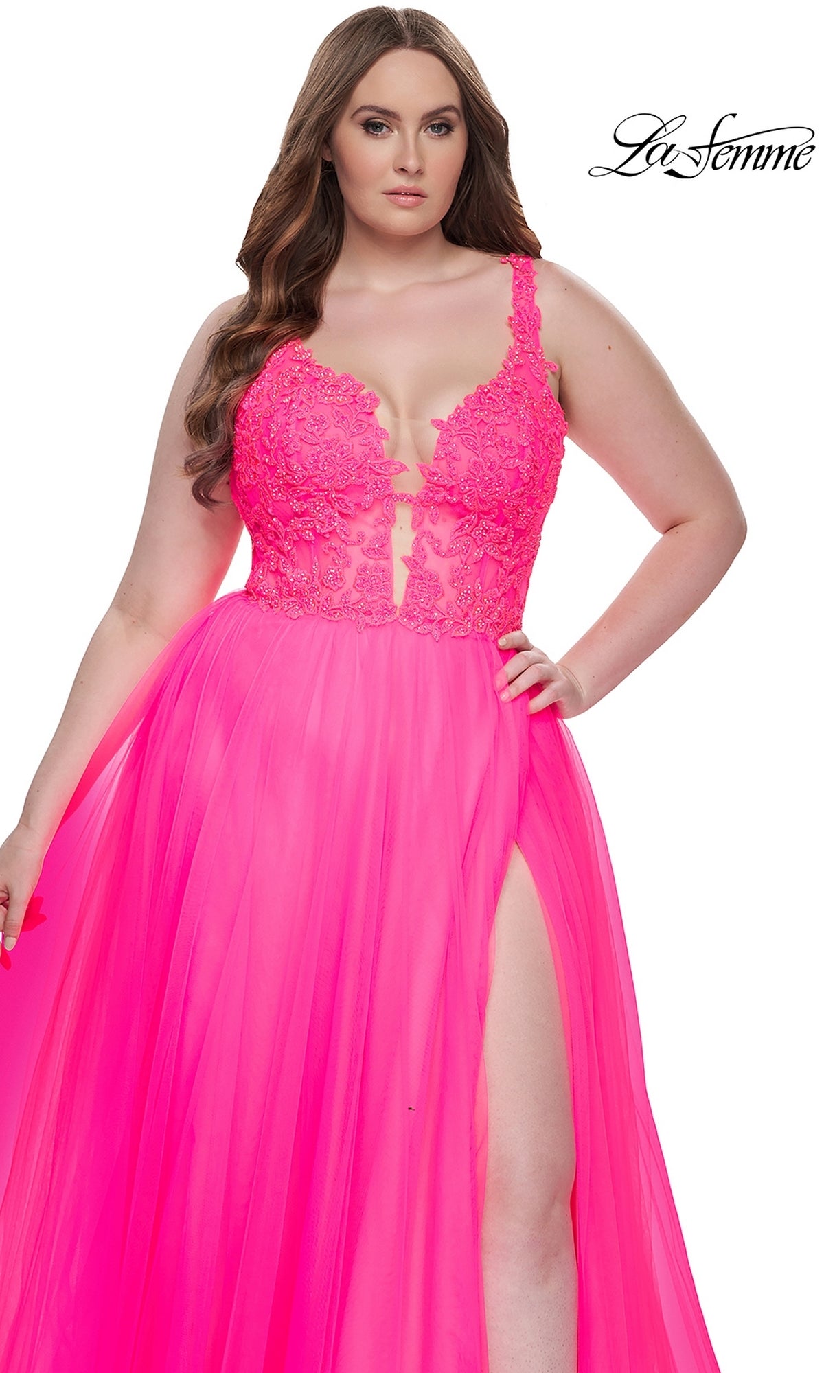 A woman wears the La Femme Long Prom Dress 31394—a bright pink gown with an embroidered lace bodice, sheer panel, and thigh-high slit. The